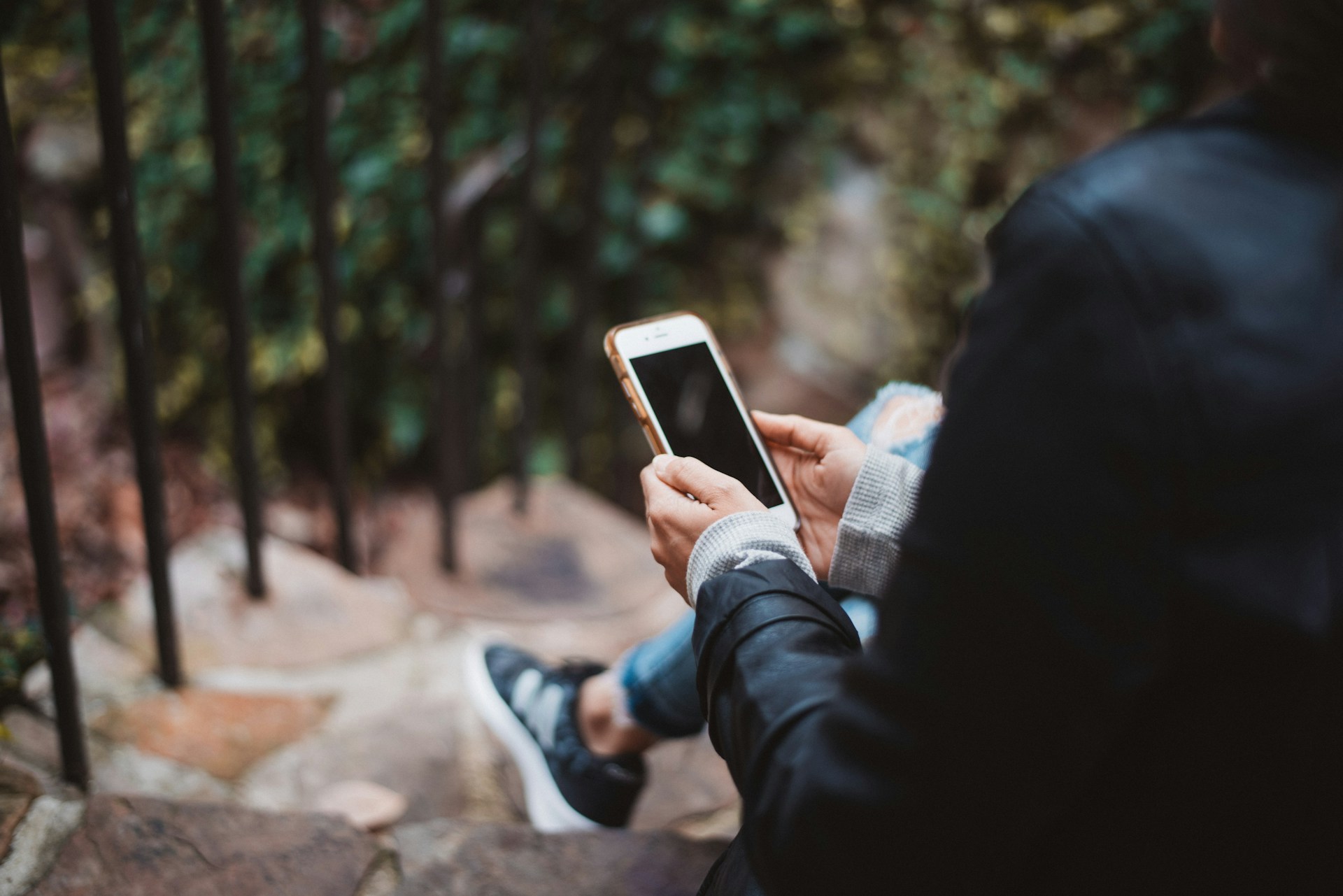 person holding smartphone sitting on steps